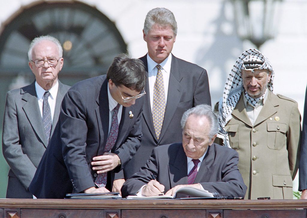 Israeli Foreign Minister Shimon Peres (C) signs the historic Israel-PLO Oslo Accords on Palestinian autonomy in the occupied territories on September 13, 1993 in a ceremony at the White House in Washington, D.C. as (from L to R) Israeli Prime Minister Yitzhak Rabin, unidentified aide, US President Bill Clinton and PLO Chairman Yasser Arafat look on. / AFP / J. DAVID AKE (Photo credit should read J. DAVID AKE/AFP/Getty Images)